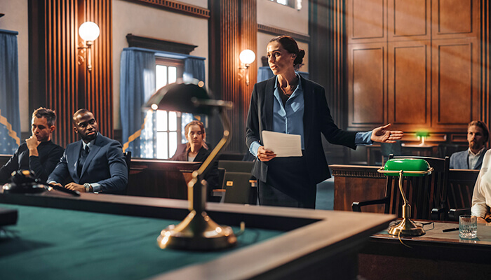 A prosecutor argues the case as the defendant and rest of the court room listen intently. 